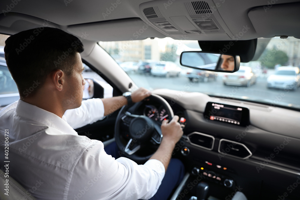 Man driving his modern luxury car, view from backseat