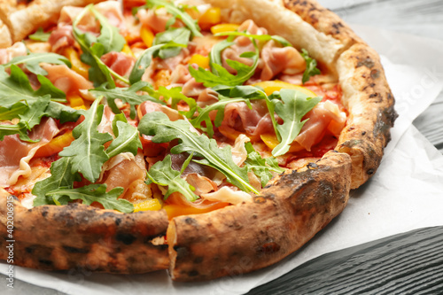 Tasty pizza with meat and arugula on grey wooden table, closeup