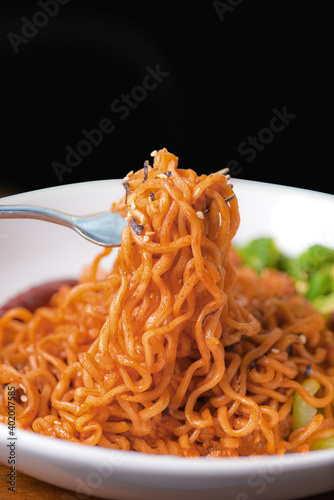 Close-up holding roll spicy noodle in bowl on black background