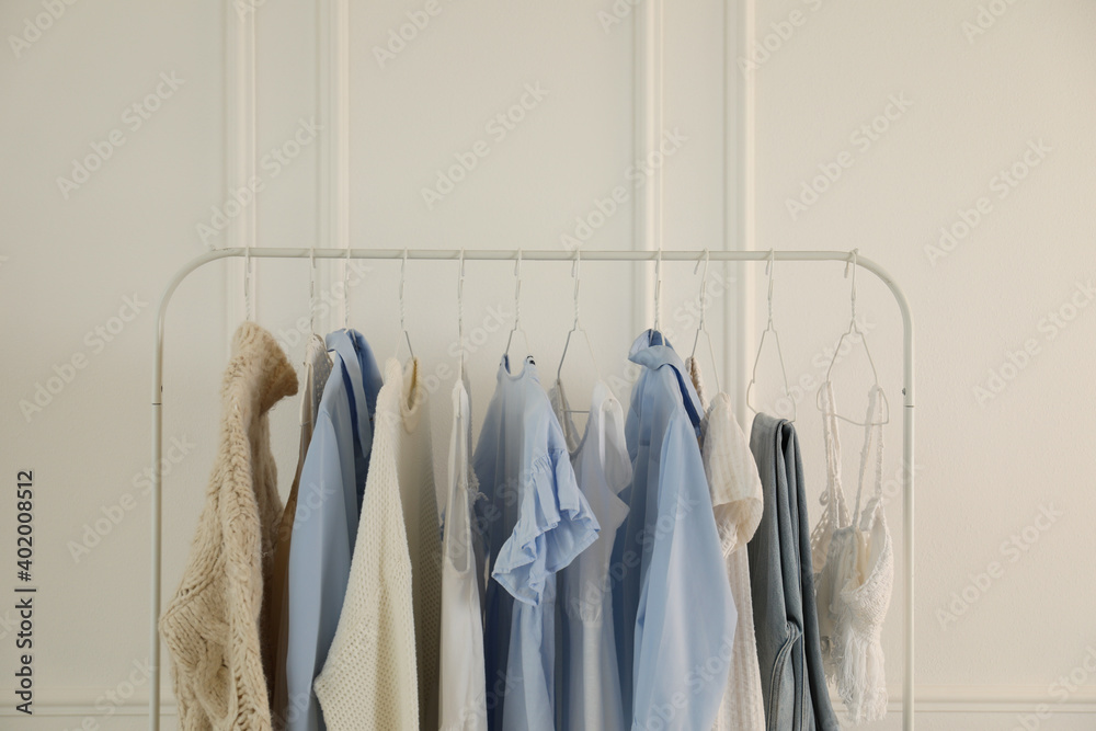 Rack with stylish women's clothes near white wall. Interior design