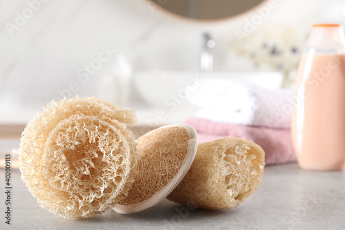 Natural loofah sponges on table in bathroom. Space for text