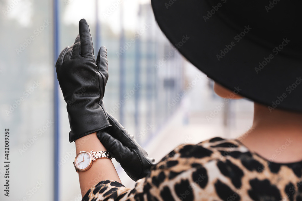 Young woman putting on stylish black leather gloves outdoors, closeup - obrazy, fototapety, plakaty 