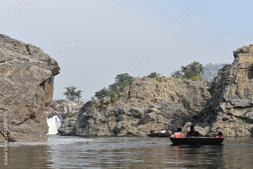 HOGENAKKAL FALLS, INDIA - DECEMBER 26 2020 group of young man Tourists wearing lifevests enjoying coracle ride river near waterfalls photo