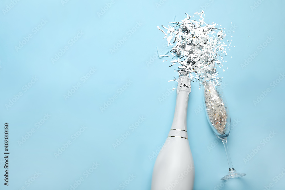 Flat lay composition with confetti, bottle of champagne and flute glass on light blue background. Space for text