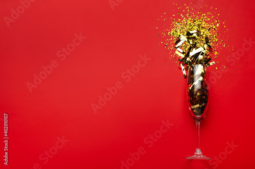 Fototapeta Naklejka Na Ścianę i Meble -  Flat lay composition with confetti and champagne glass on red background. Space for text