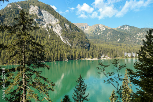 A view on the Pragser Wildsee, a lake in South Tyrolean Dolomites. High mountain chains around the lake. The sky and mountains are reflecting in the lake. Dense forest at the shore. Autumn vibe. Relax