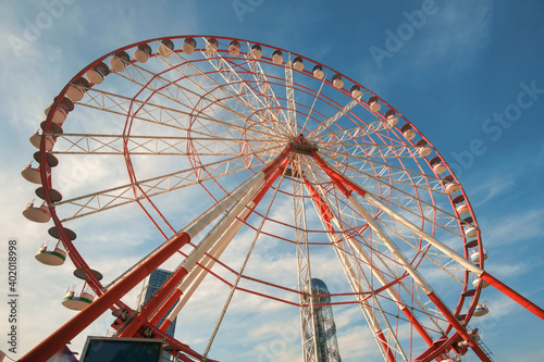 A large red and white Ferris Wheel against a blue sky