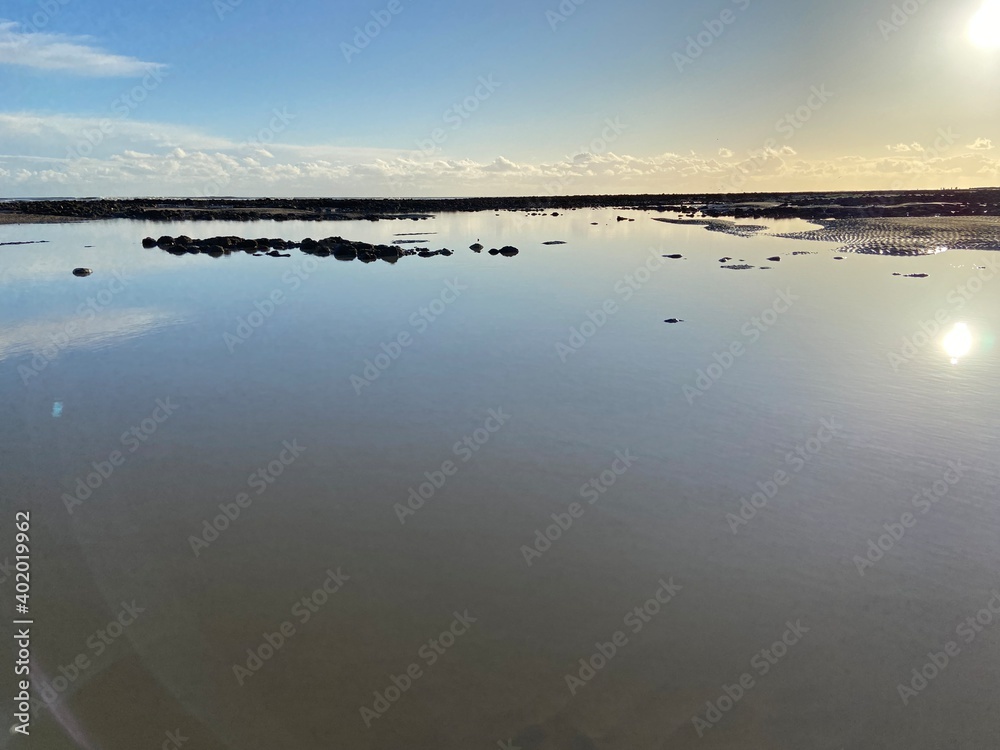 Pett Level Beach at Sunset. pool of sea ocean water rocks in foreground. Winchelsea Beach meets the cliffs on the South coast of England East Sussex UK