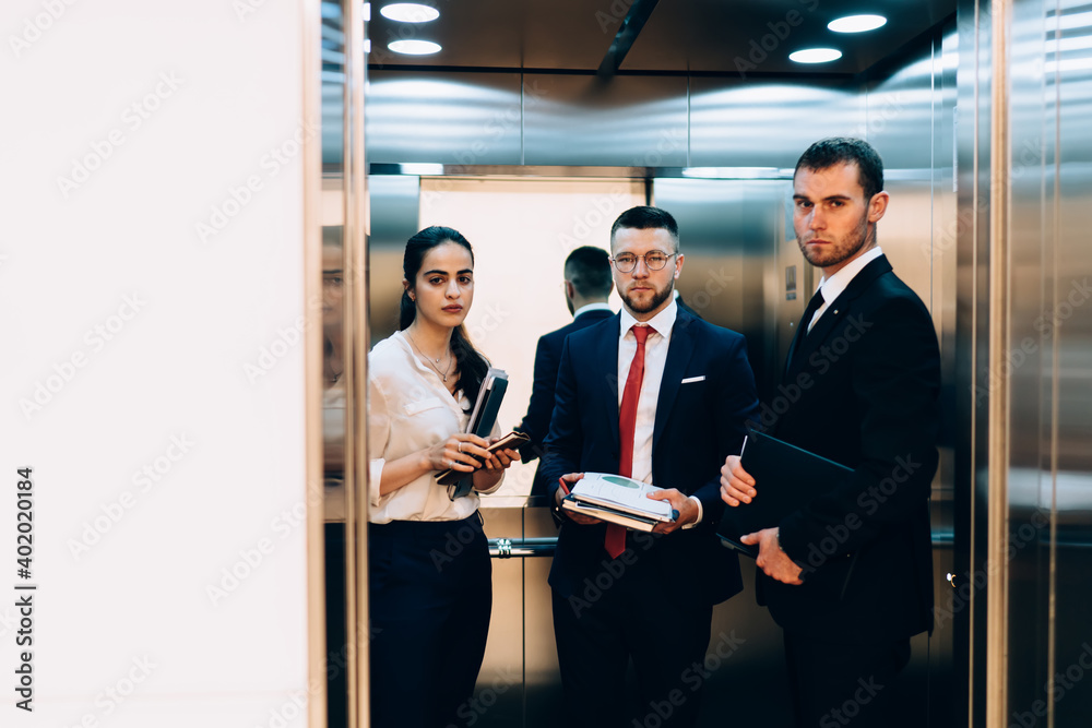 Group of colleagues standing together in elevator in office