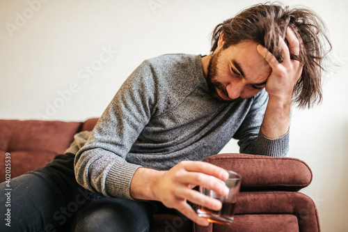 from below Alcohol addiction at young age. Caucasian male cannot stop drinking alcohol, male with whisky glass. Loneliness, depression and alcoholism photo