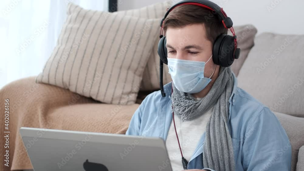 Young man wearing a protective mask work from home. Coronavirus pandemic. Freelance and distance working. Young man wearing a protective mask work from home. Coronavirus pandemic. Freelance and distance working.