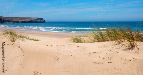 sandy dunes Bordeira beach with grass, ocean with waves at the horizon, West algarve portugal photo