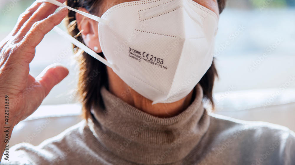 Corona Schutzmaske / FFP2 Atemschutzmaske / Frau / Maske aufsetzen / Freizeit