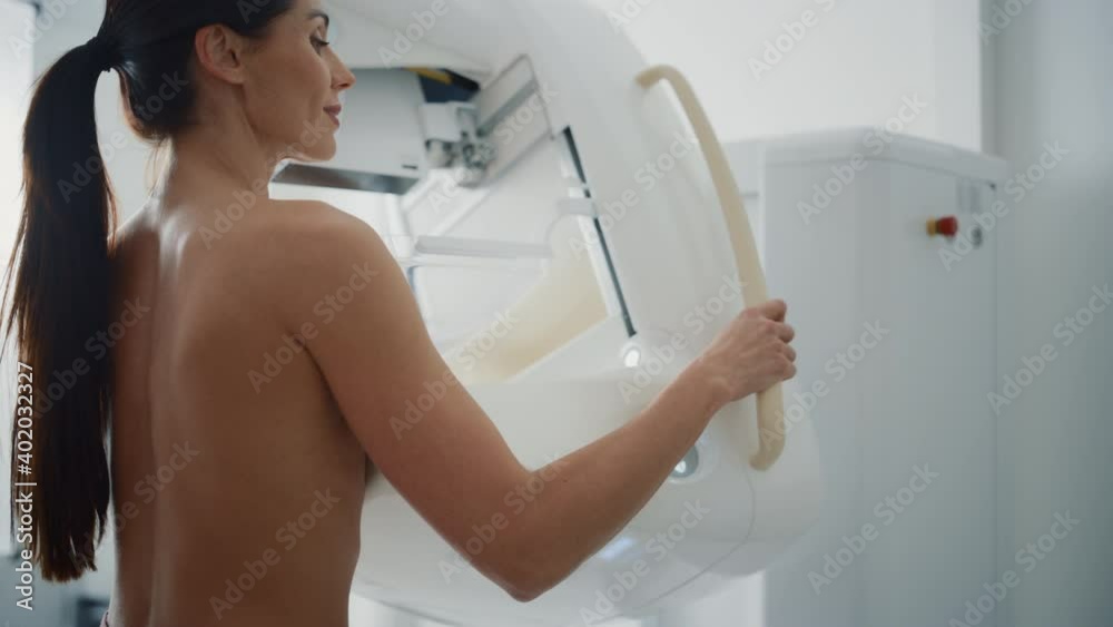 In the Hospital, Portrait Shot of Topless Multiethnic Female Patient Undergoing Mammography Screening Procedure. Healthy Adult Caucasian Woman Does Cancer Preventive Mammogram Scan in Radiology Room. In the Hospital, Portrait Shot of Topless Multiethnic Female Patient Undergoing Mammography Screening Procedure. Healthy Adult Caucasian Woman Does Cancer Preventive Mammogram Scan in Radiology Room.
