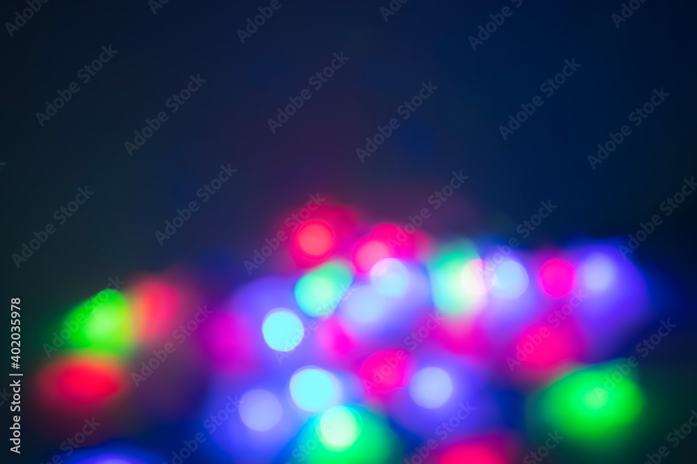 Glowing colorful garland on blue  background. Christmas and New Year concept. Defocus.