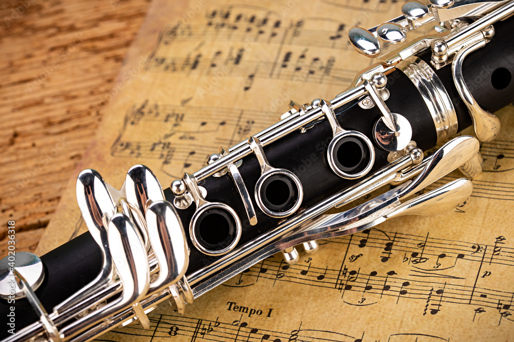 black wooden clarinet silver woodwind musical brass instrument with old  vintage music sheet paper retro oak wood background. classic orchestra  symphony background. Stock Photo | Adobe Stock