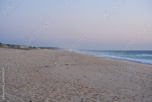 Fisherman fishing on a Comporta empty beach at sunset in Portugal