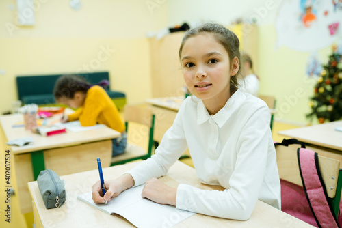 A student at school at the lesson at the table with a pencil case and a book. Schooling