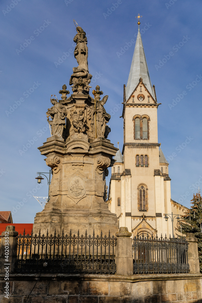 Church of the Assumption of the Virgin Mary and Marian column, Christmas market at Square Namesti starosty Pavla in Kladno in sunny day, Central Bohemia, Czech Republic
