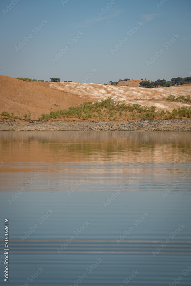 Desert like hill landscape with reflection on the water on a dam lake reservoir with blue sky in Terena, Portugal Desert like hill landscape with reflection on the water on a dam lake reservoir with blue sky in Terena, Portugal