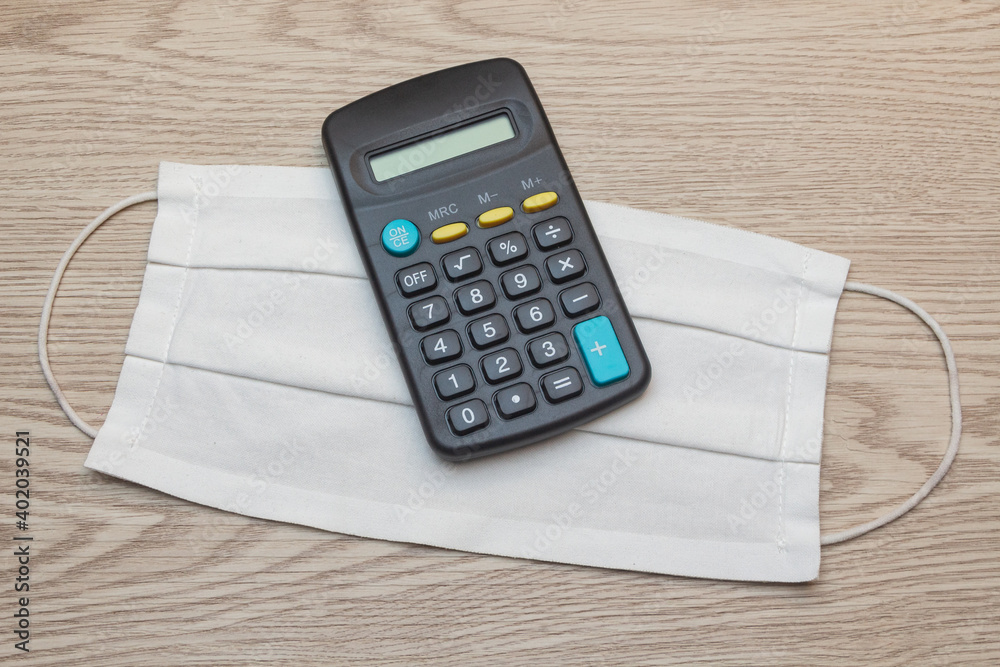 Fabric mask and calculator on wooden background Fabric mask and calculator on wooden background