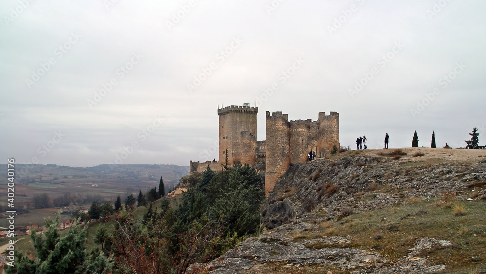 Obraz premium Turistas visitando el castillo de Peñaranda de Duero, fortaleza del siglo XI situado en una colina junto al pueblo de Peñaranda de Duero, en Burgos, España.