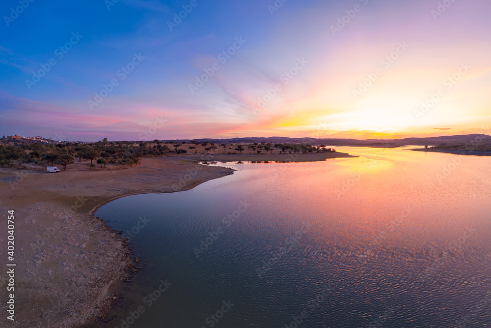 Drone aerial panorama of a dam lake reservoir with a camper van at sunset in Terena, Portugal