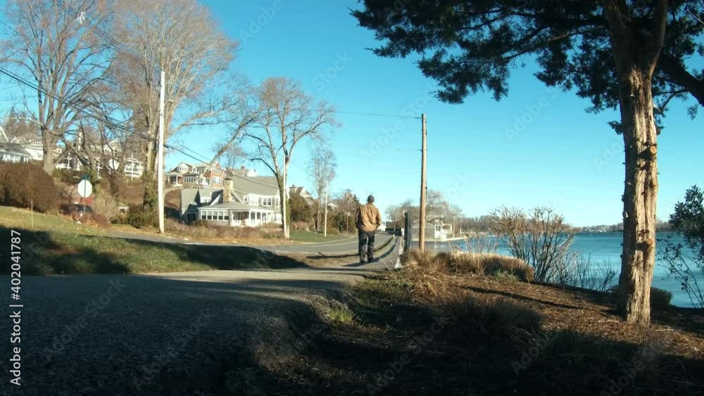 Man walking alone by the water side with beautiful blue sky. Static. Man walking alone by the water side with beautiful blue sky. Static.