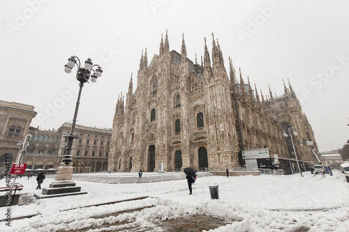 Milan, Italy - December 28, 2020: street view of Milan during the snow blizzard of late December in Piazza del Duomo, people are visible in the distance. photo