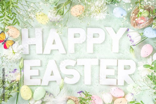 Happy Easter concept. Spring Easter holiday top view  flat lay background with easter eggs in nests and spring flowers. Easter greeting card background with copy space. © ricka_kinamoto