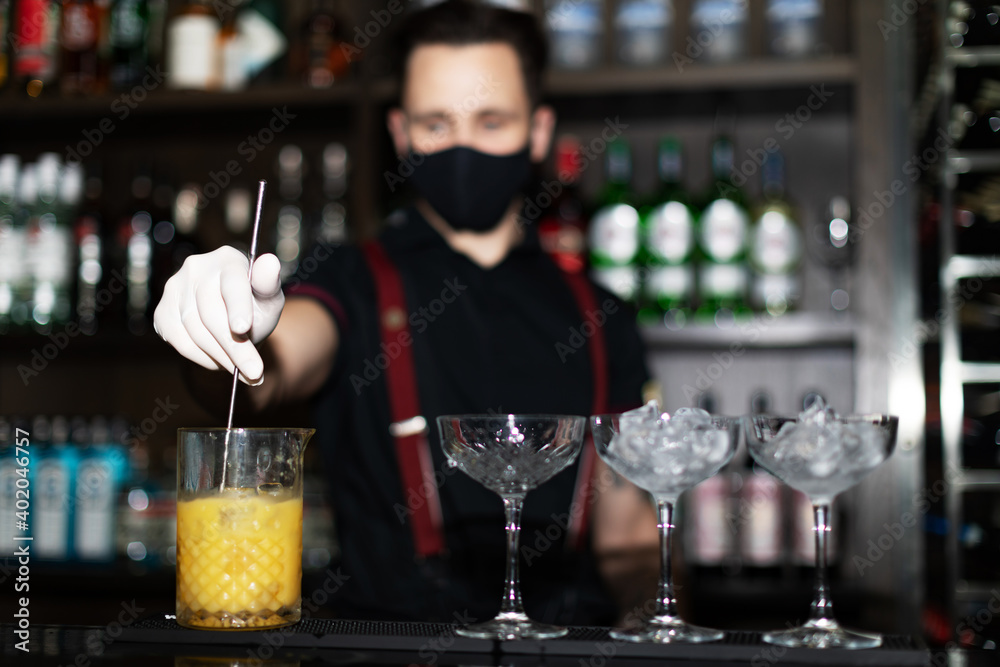 Bartender making refreshing coctail on a bar background. Dark moody style. Focus on coctail.