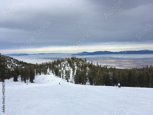 Scenic winter landscape at a ski resort, with skiers on slopes, on a cloudy day