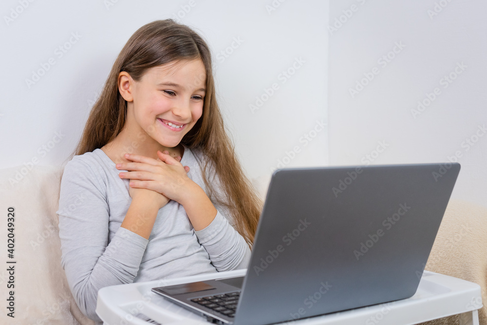 Portrait of attractive cute happy smiling girl 6-7 old sitting using laptop indoor white background distance learning Portrait of attractive cute happy smiling girl 6-7 old sitting using laptop indoor white background distance learning