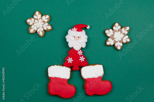 Santa Claus in gingerbread boots on a green background. Christmas composition.