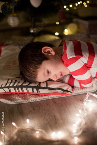 Boy sleeping under Christmas tree