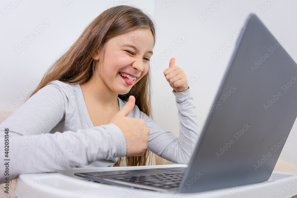 Portrait of attractive cute happy smiling girl 6-7 old sitting using laptop indoor white background distance learning Portrait of attractive cute happy smiling girl 6-7 old sitting using laptop indoor white background distance learning