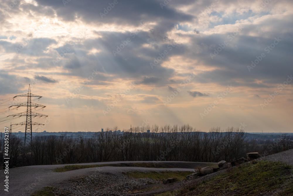 View over the Ruhr area, on the horizon the silhouette of the city of Essen, in dramatic light and cloudy sky View over the Ruhr area, on the horizon the silhouette of the city of Essen, in dramatic light and cloudy sky