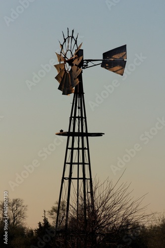 windmill at sunset with a colorful sky and tree's north of Hutchinson Kansas USA out in the country.