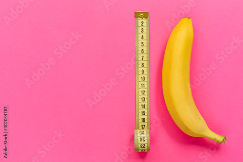 Foto Yellow banana with measurement tape on pink background