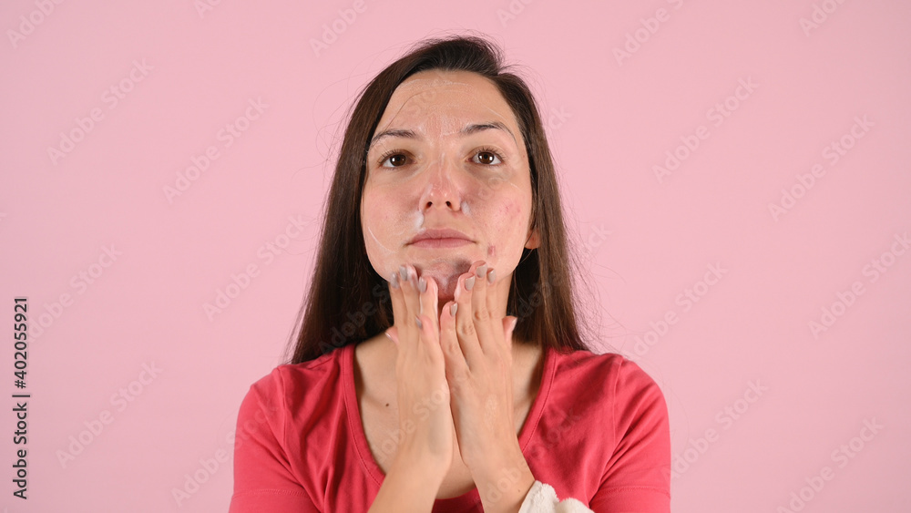 Beautiful middle-aged woman applying moisturizer on her face on pink background. Problem skincare concept Beautiful middle-aged woman applying moisturizer on her face on pink background. Problem skincare concept