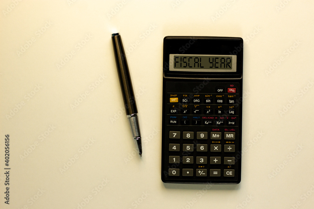 Fiscal year symbol. Calculator with words 'fiscal year', metalic pen. Business and fiscal year concept. Beautiful white background, copy space. Fiscal year symbol. Calculator with words 'fiscal year', metalic pen. Business and fiscal year concept. Beautiful white background, copy space.