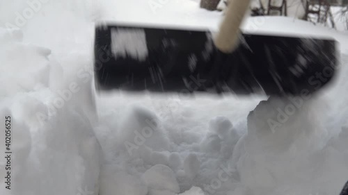 Close-up of a shovel, a man cleans snow with a shovel in his yard. Winter in Russia covered the yard with snow