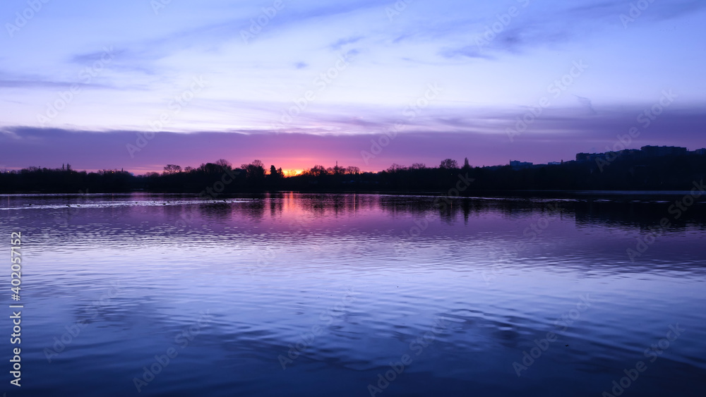 Amazing sunrise or sunset in rural scene. Symmetry of the sky in a lake. Clouds reflecting on the water. Quiet relaxing scene with a beautiful colorful cumulonimbus.