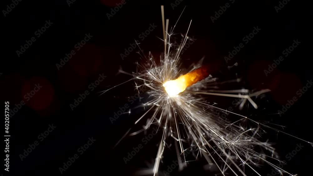 Sparkler burns brightly against a background of bright bokeh circles. Close-up. Sparkler burns brightly against a background of bright bokeh circles. Close-up.