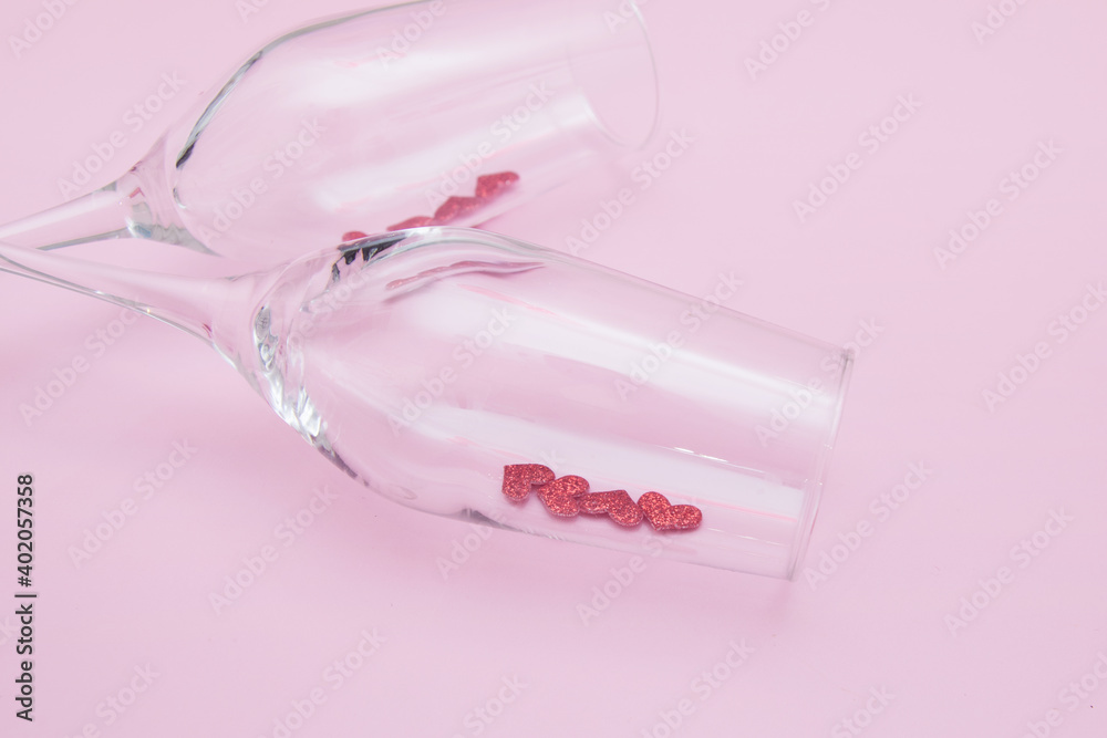 Two glasses with red hearts lie on a pink background - romantic date for Valentine's Day concept Two glasses with red hearts lie on a pink background - romantic date for Valentine's Day concept