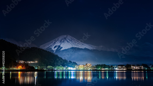 Superbe panorama sur le Mont Fuji vue de nuit depuis le lac de Kawagushiko avec la ville d'Oishi éclairée, Japon photo