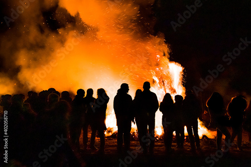 silhouettes of group of people gathering around a huge easter fire