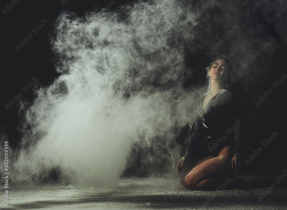 Obraz premium young beautiful caucasian woman with long hair is dressed in a sports black bodysuit and sits on the floor