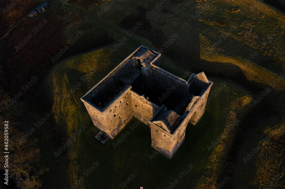 Medieval Castle from top down angle in Scotland at sunrise with dramatic casting light 