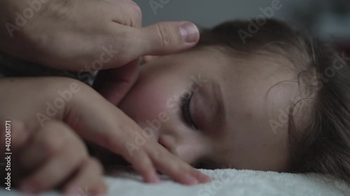 Relaxation, Sweet Dreams, Childhood, Family Concepts - Tight close up preschool toddler kid girl Sleep on Bed in Dark Room. father male hand gently strokes daughter's hand face, covers with blanket